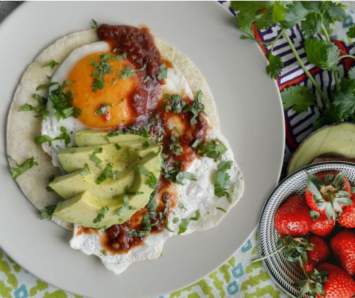 Huevos rancheros con tortilla, fresa, aguacate, tomate y cebolla