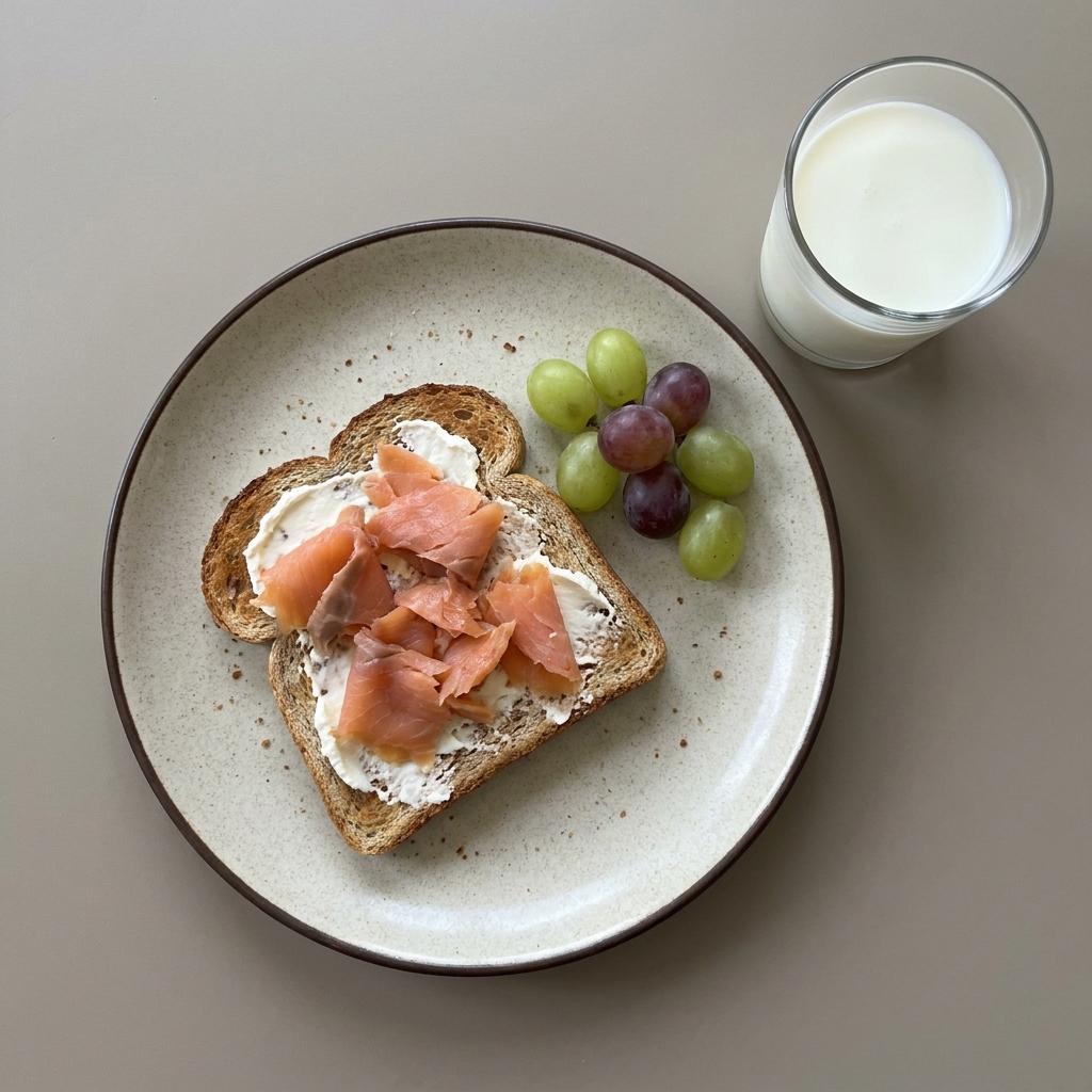 Pan tostado con queso crema y salmón ahumado, con uvas y vaso de leche