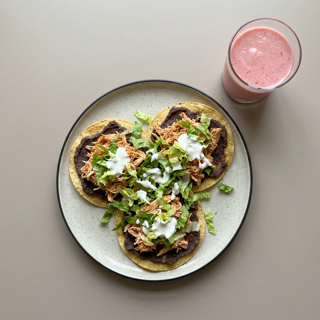 Tostadas de tinga de pollo con frijoles refritos y crema, con licuado de fresa