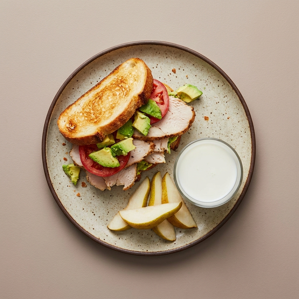 Sandwich de pavo con jitomate y aguacate, con pera y vaso de leche