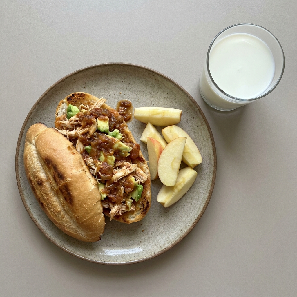 Torta de pollo en salsa de jitomate con aguacate, acompañada de manzana y vaso de leche