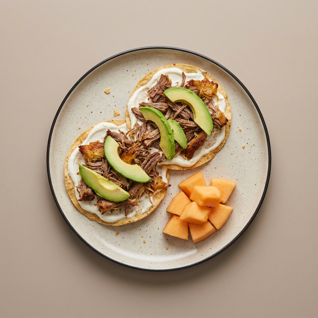 Tostadas de carne res deshebrada con jocoque y aguacate, acompañadas de melón picado