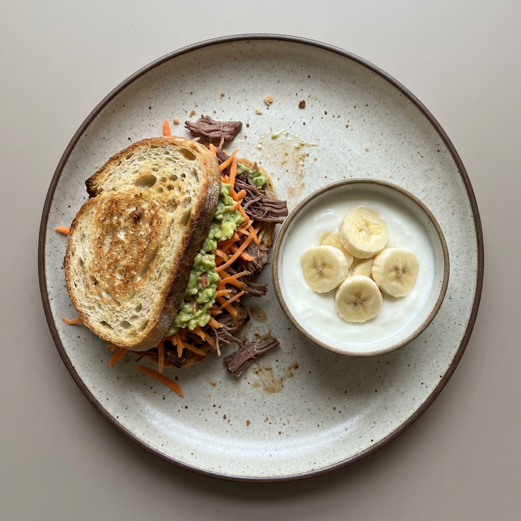 Sandwich de carne res deshebrada con zanahoria y guacamole, con bowl de yogurt con plátano