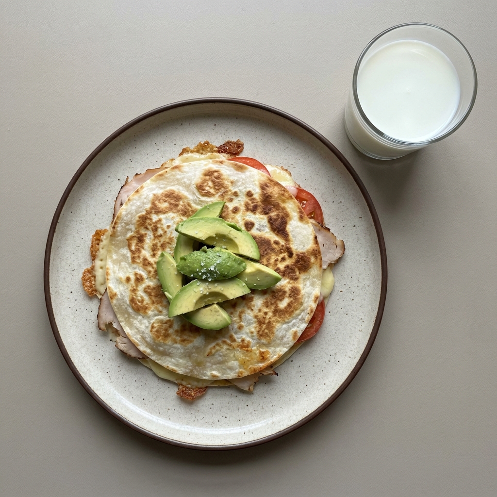 Sincronizada con pechuga de pavo, jitomate y aguacate, con vaso de leche